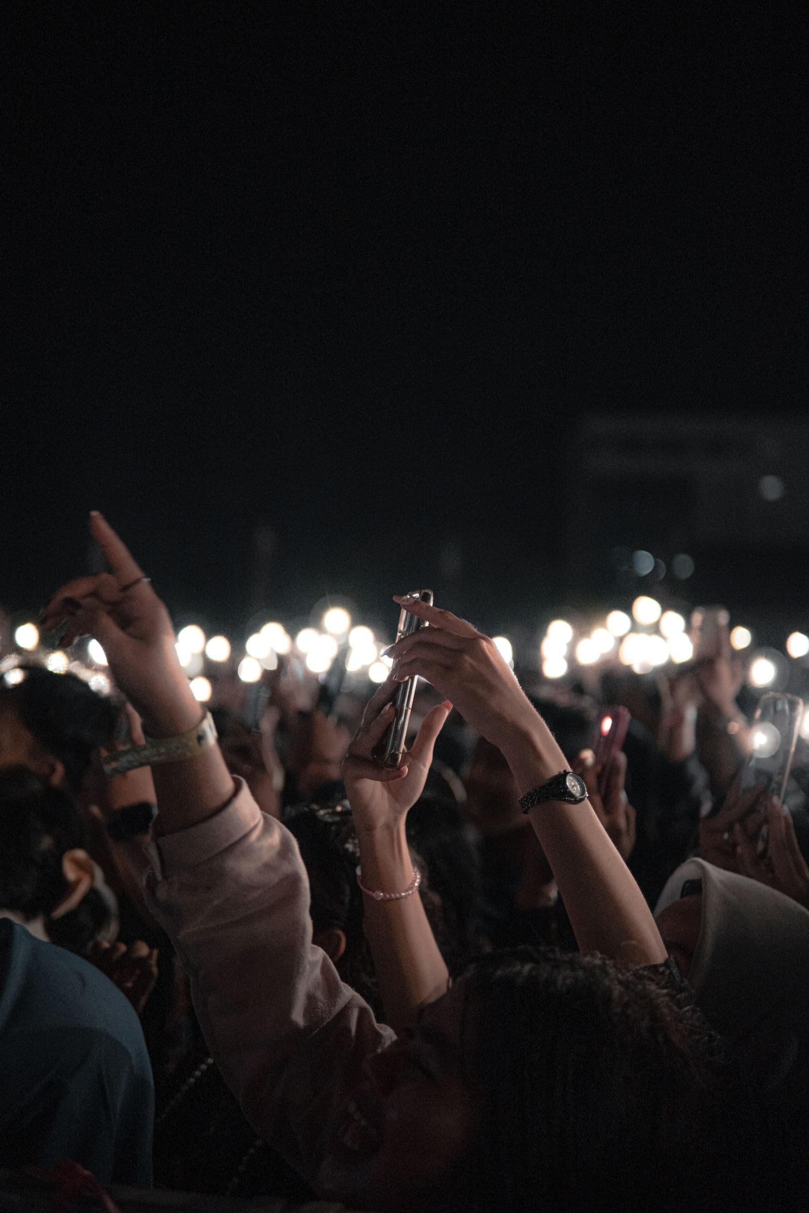 Crowd at a nighttime show with phones held up toward the stage