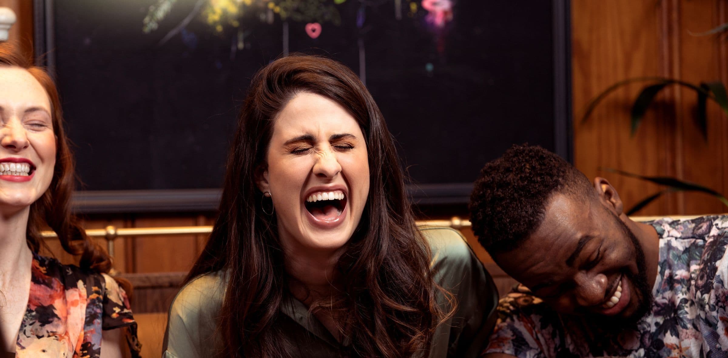 Three friends laughing together at a dimly lit bar
