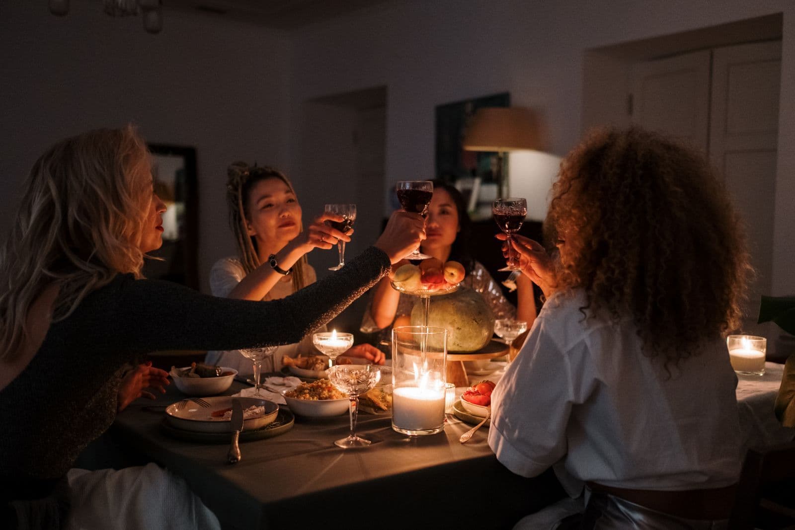 Friends raising wine glasses around a candlelit dinner table