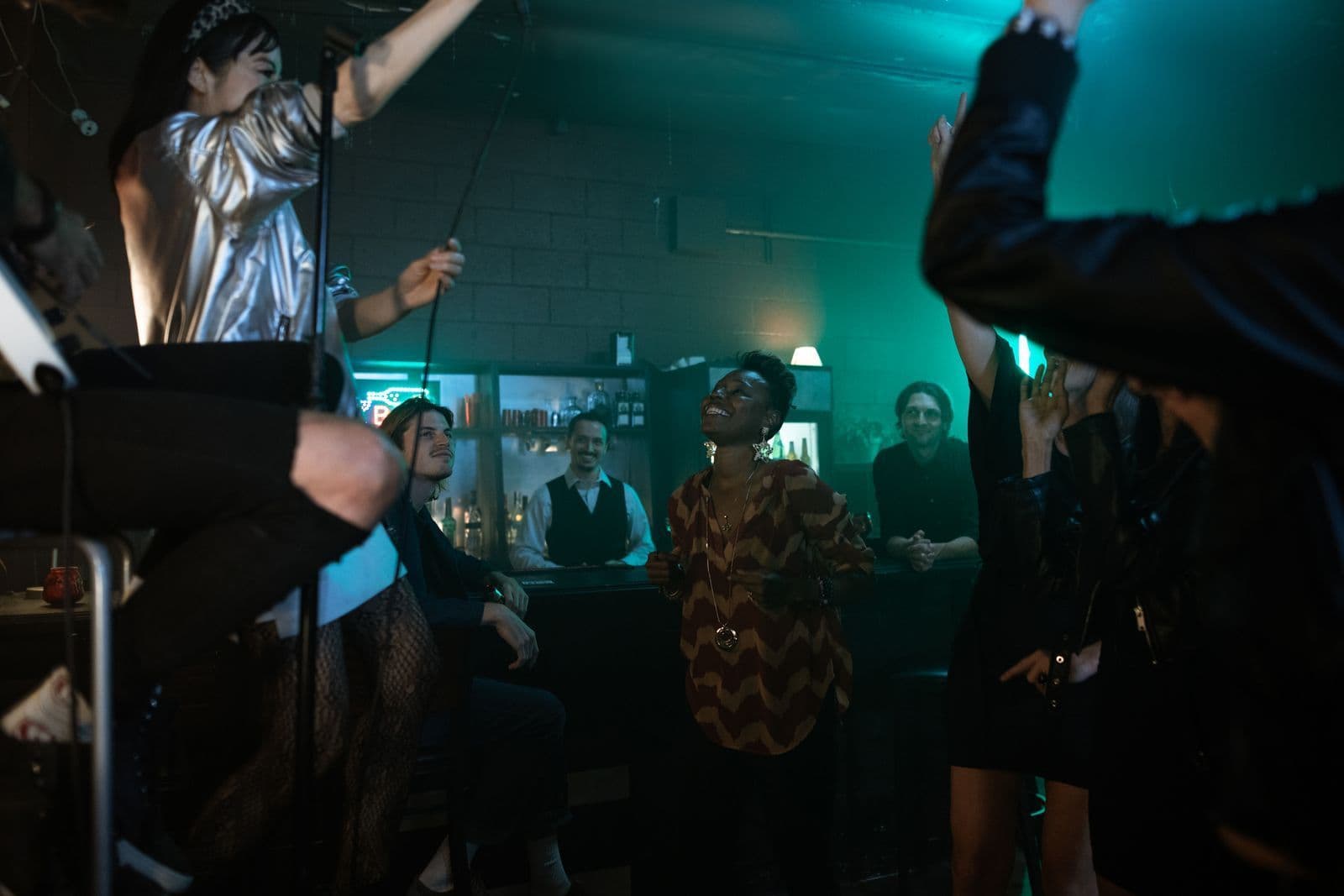 Friends dancing in a crowded bar under teal and warm lights