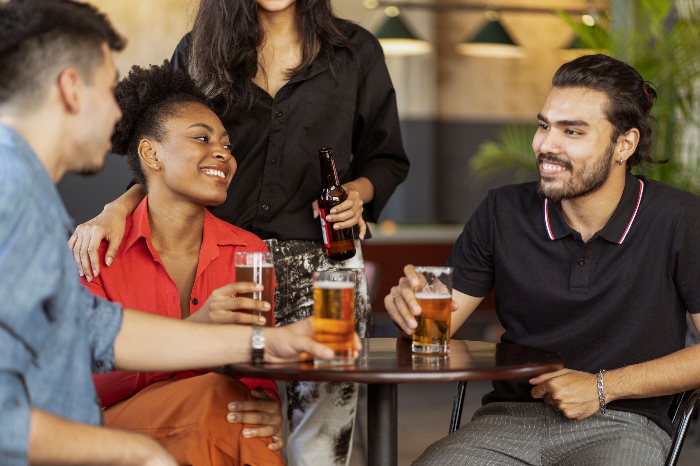 A diverse group of friends laughing and raising drinks around a small table at a bar