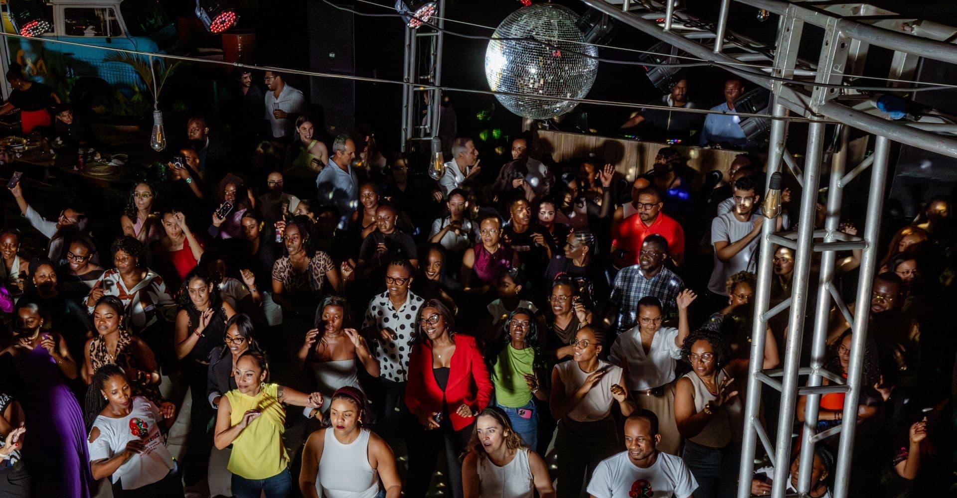 A diverse crowd dancing under a disco ball at a packed after-dark event