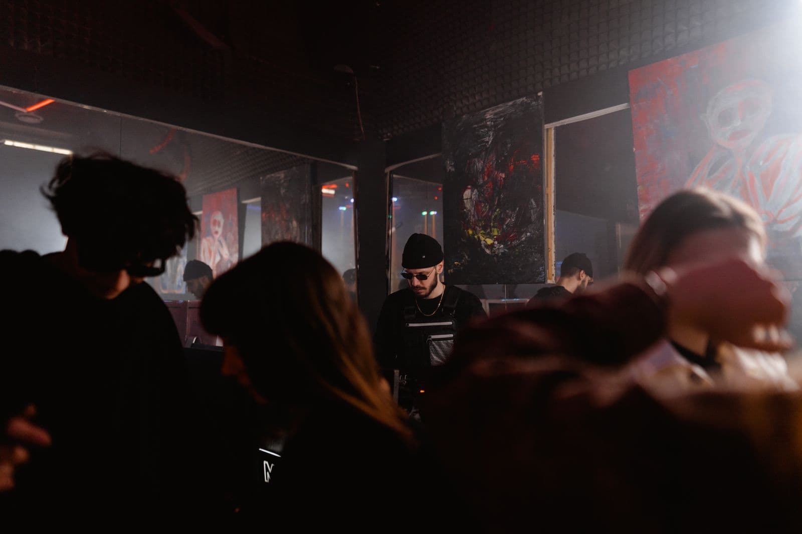 A crowd dancing in a dim club under moody colored lights